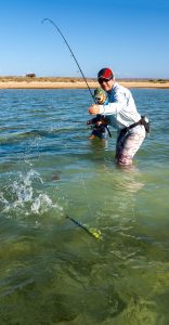 jo starling is about to bring a chevron trevally to hand, with daughter by her side, knee deep in the waters off exmouth, WA.
